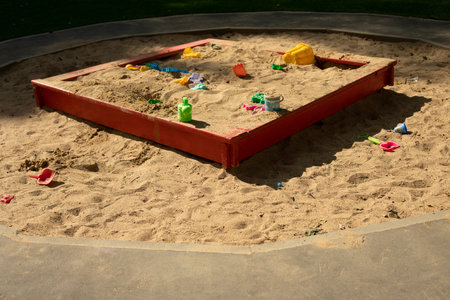 Children's playground with sand. Children's sandbox on street. Place for game kids. Sand with toys. Forgotten toys.の写真素材
