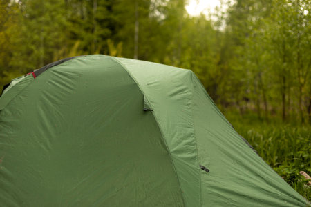 Tourist tent in forest. Tent for sleeping in nature. Equipment for going to park. Awning protects against rain.の写真素材