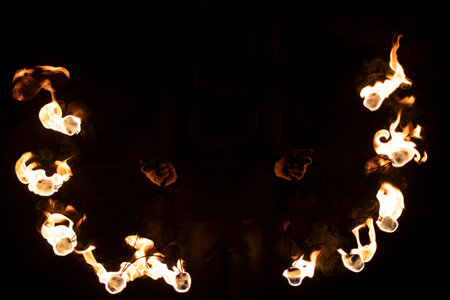 fireshow in dark. Two steel fans with hot flames. Burning kerosene.の写真素材