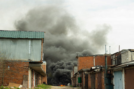 fire in the city. Black smoke in the sky. Ignition of industrial zone. burning garbage.の写真素材