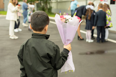 Child holds flowers. Schoolboy with bouquet for teacher. boy at party. Details of the first day of school.の写真素材