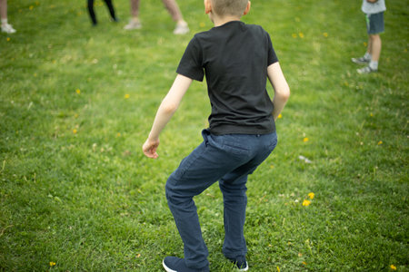 Child on green grass. Schoolboy plays on lawn in summer. Active holidays. child from behind.の写真素材