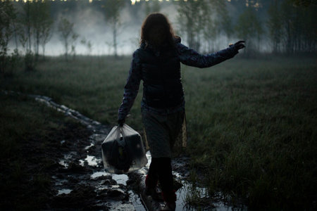 Girl walks in fog in the morning. Rest in wild. Fog in swamp. Man carries things to water.の写真素材