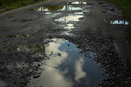 Large puddle on asphalt. Road with pits. Puddles on road. Rural highway details.の写真素材