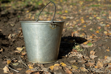 Steel water bucket. Bucket of water in garden. Garden tools for watering earth. Object stands on ground.の写真素材