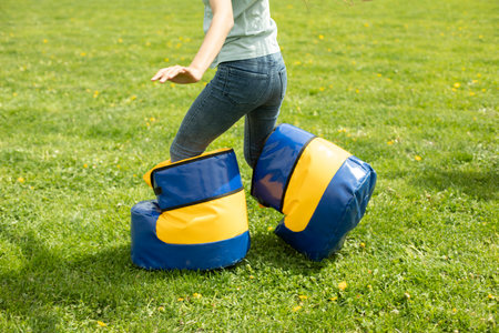 Child plays on green grass. Entertainment for children in the park. Fun running contest. Funny shoes.の写真素材