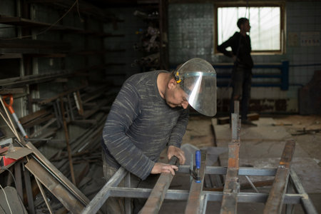 Welder holds metal. People in metal workshop. work in garage. Worker in protective mask.の写真素材