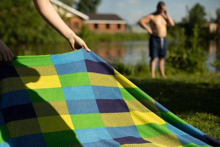 Relax in summer on the beach. Colored blanket on lake. Details of picnic in the park. Fabric with linear pattern.の写真素材