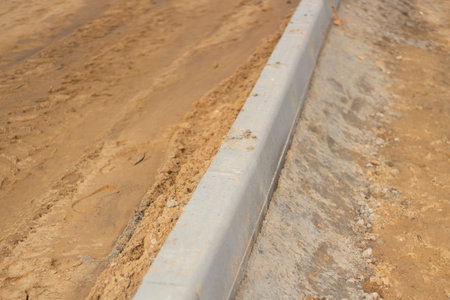 New messes on road. Repair of roads. Details of construction work. Concrete blocks are fixed in ground. Background construction sites.a.の写真素材