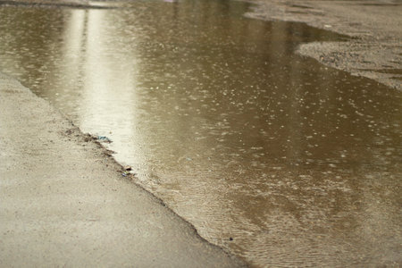 rain outside. Large puddle in yard. Wet weather. surface of puddle. water on road.の写真素材