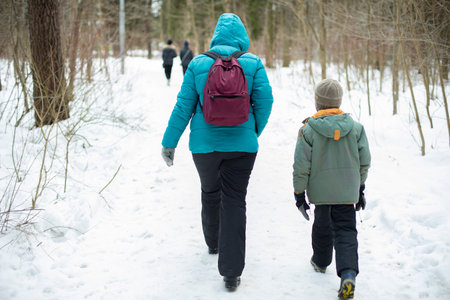 mother and son in the park. People walk in winter along the path in the park. Parent with child on walk in woods.の写真素材