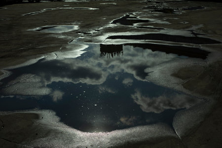 Puddle on pavement. after rain. Road in pits. Reflection of sky in puddle.の写真素材