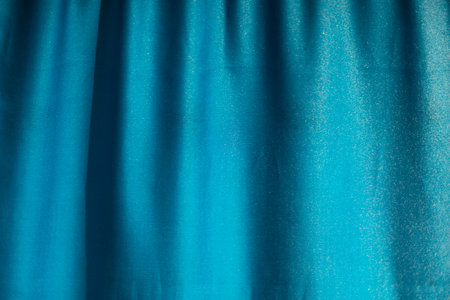 Blue fabric on window. Curtain in light. Folds on fabric.の写真素材