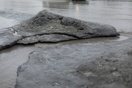 Dirty water flows on asphalt. Flow of water along road. Cloudy liquid. Wastewater in city.