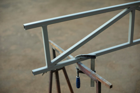 Steel part on street. Metal profile with holder. Steel construction parts. Workbench for work.の写真素材