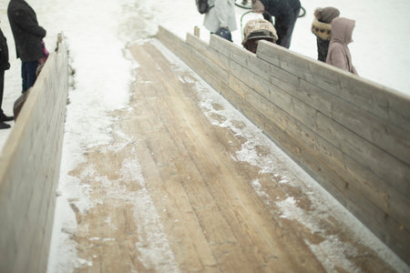 Child rolls down slide in winter. Boy on slide. Preschooler glides on board.の写真素材