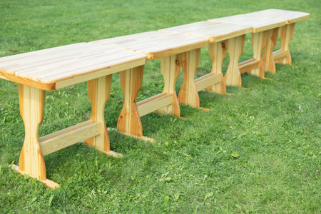 Wooden tables on green grass. Tables in park. Preparing holiday in open air. Furniture made of wood.の写真素材