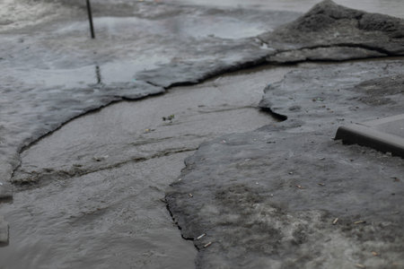 Dirty water flows on asphalt. Flow of water along road. Cloudy liquid. Wastewater in city.