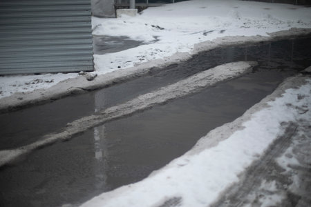 Melted snow on road. Large puddle in spring. Lots of water on asphalt. Melting snow in the city.の写真素材