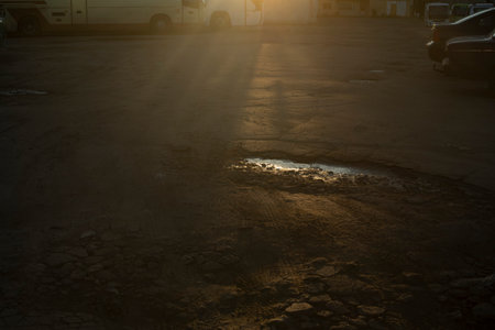 Light on the asphalt. Rays of light on the road. A pit in the asphalt. Pavement.の写真素材