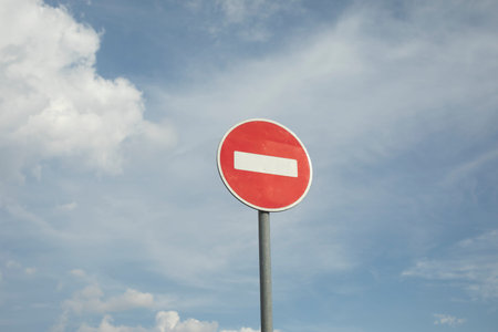 Stop sign on sky background. Road sign prohibiting traffic. Red circle and white line. Sign on pole.