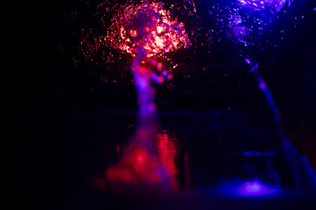 Colored stream of water in the dark. Flow Details. Water illumination. Fountain in the city at night.の写真素材