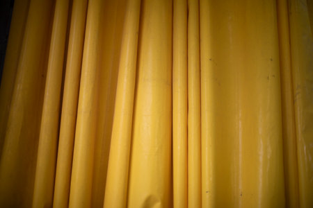 Yellow rubber tarpaulin at car wash. Moisture protection. Texture of the material is yellow. Folds on the dawn.の写真素材