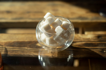 Sugar on table. Sugar in cubes. Treat to tea. Beverage sweetener. Glass bowl.の写真素材
