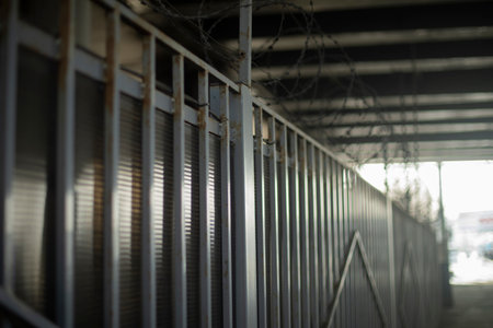 Fence under bridge. Steel fence with barbed wire. Steel profile. Closed area.の写真素材