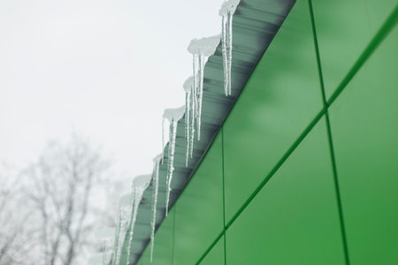 Icicles on the roof. Ice on building. Icing of visor. Melting snow. Icicle hanging on visor.の写真素材