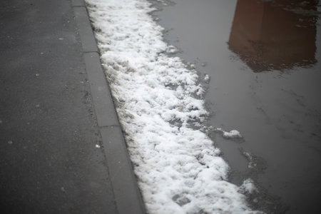 Melted snow on road. Large puddle in spring. Lots of water on asphalt. Melting snow in the city.の写真素材