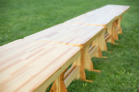 Wooden tables on green grass. Tables in park. Preparing holiday in open air. Furniture made of wood.の写真素材