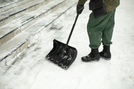 Snow shovel cleaning. Snow in yard in winter. Man cleans path from precipitation. Shovel cleaning details.の写真素材