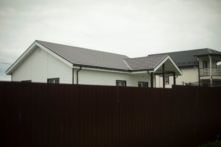 Country house behind fence. Lodge in village. Roof of building. Private sector.の写真素材
