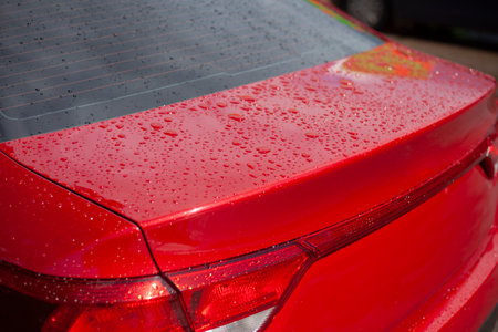 Trunk of a red car. Water droplets on the body. The car is in the parking lot. Red body of transport.の写真素材