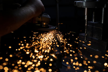 Sparks from grinding metal. Bright lights in dark. Cutting steel. Metal profile processing. Bright sparks from high temperature.の写真素材