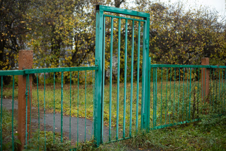 Green fence. Entrance to the fence. Details of the park. Steel grating.の写真素材