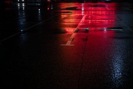 Red light on the asphalt. Empty parking lot at a shopping center. Empty parking spaces at night. Wet asphalt.の写真素材