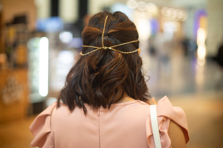 The girl's dark hair. Beautiful hairstyle. Chain on the head. Beautiful girl in pink dress.の写真素材