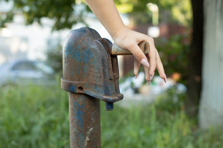 Water from well. Lever press. Girl presses handle of hydrant. Drinking water. Details of rural life.の写真素材