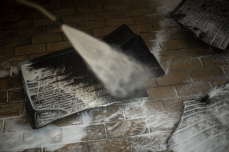 Washing dirt off mat from car. Mat under running water. Jet under high pressure. Soap solution on...
