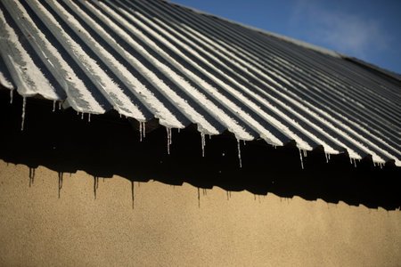 Steel roof slope. Icicles on the roof. Garage roof Steel profile on a building.