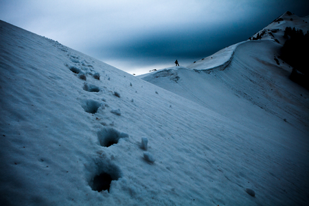 Hiker silhouette with snow tracksの写真素材
