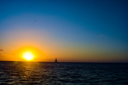 Sunset in the sea with a sailboat on the horizon.の写真素材