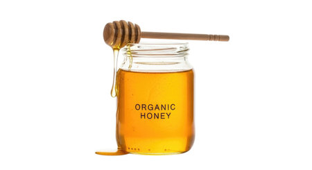 A small glass jar filled with golden honey, with a wooden honey dipper resting on top. The jar has the text 'ORGANIC HONEY' printed on it. The object is isolated on a transparent background.の素材