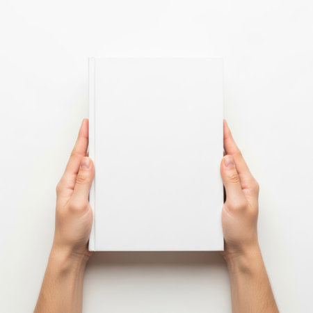 A pair of hands holding a blank white book against a plain white background.の素材