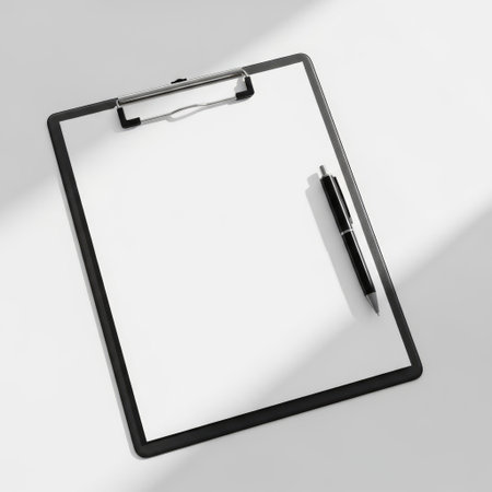 A black clipboard with a pen resting on it, set against a plain white background. The clipboard is empty and the pen is positioned diagonally.の素材