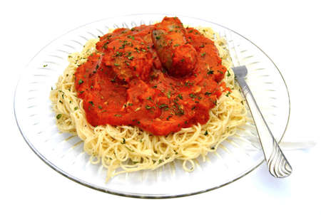 A meatball and sausage on top of spaghetti の写真素材