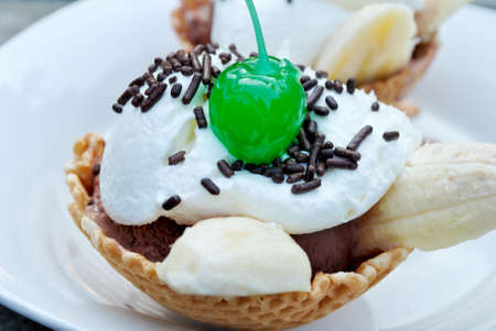 An ice cream sunday in a wafflw bowl with a green cherry の写真素材