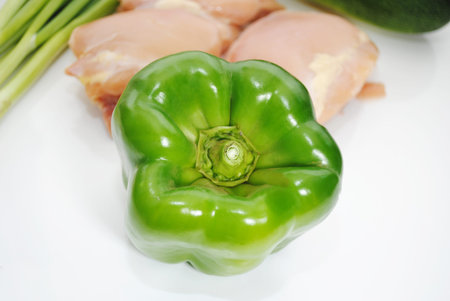 Bright Green Pepper In Front of Raw Chicken Thighsの写真素材